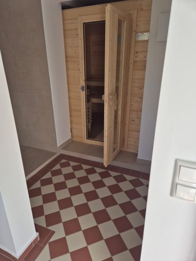Eingang zu einer Sauna mit offener Tür und gefliester Bodenfläche.