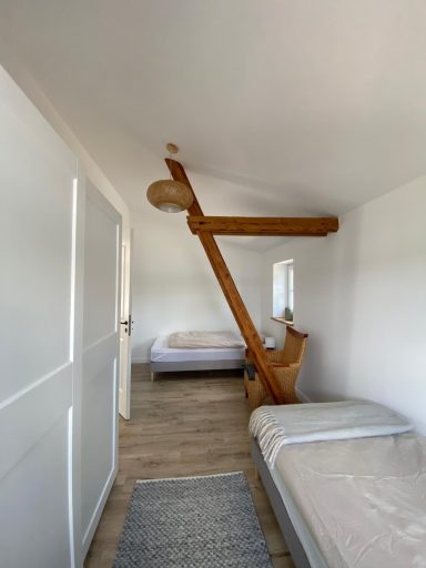Schlafzimmer mit zwei Betten, Holzbalken und neutralem Farbton.