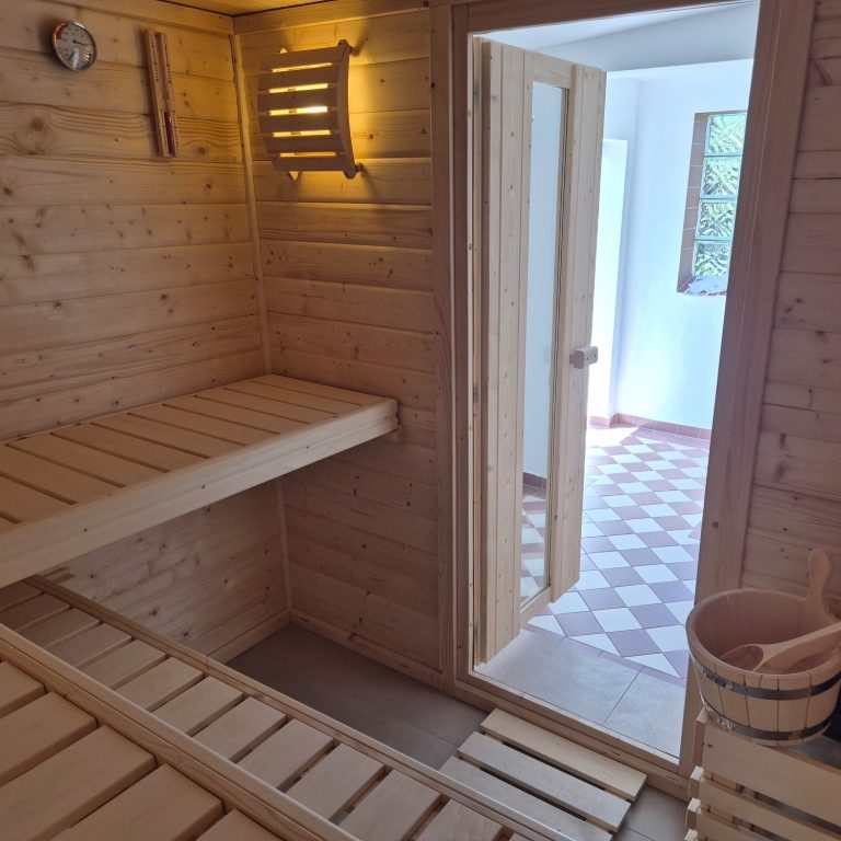 Moderne Sauna mit Holzverkleidung, Steinbrunnen und gedämpfter Beleuchtung.