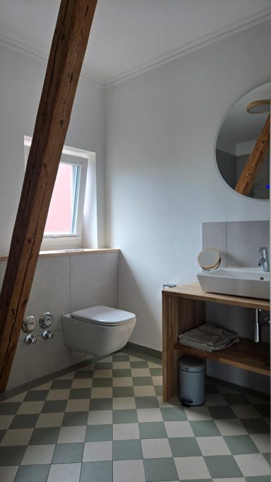 Heller, moderner Badezimmere mit WC, Waschbecken und Holzregalen.