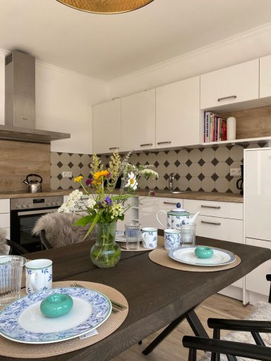 Moderne Küche mit Holzdetails, Blumenarrangement und gedecktem Tisch.