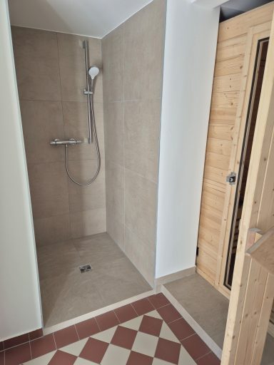 Moderne Dusche mit hellem Fliesenboden und Holzdetails im Innenraum.