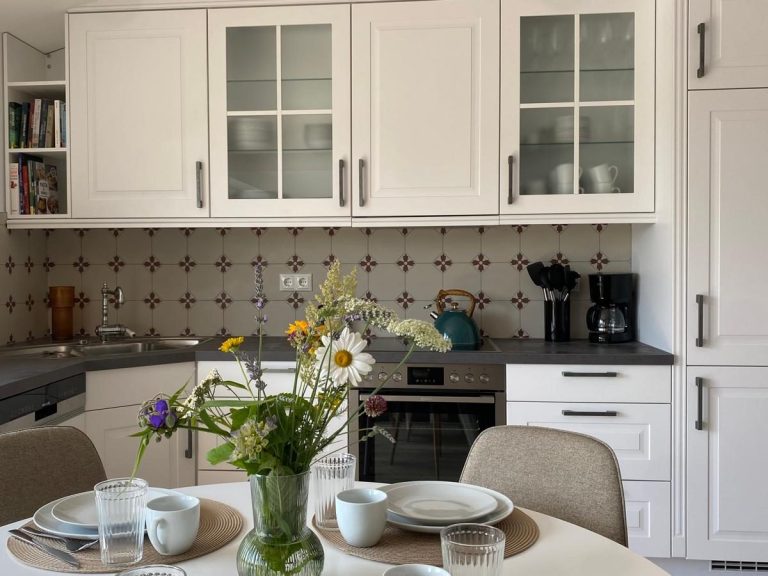 Moderne Küche mit hellen Möbeln, Tischgedeck und Blumenarrangement.